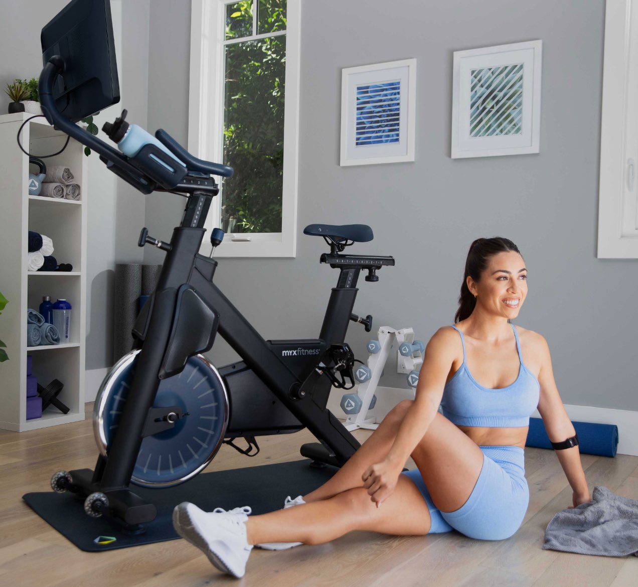 Woman sitting and stretching next to her new excercise bike